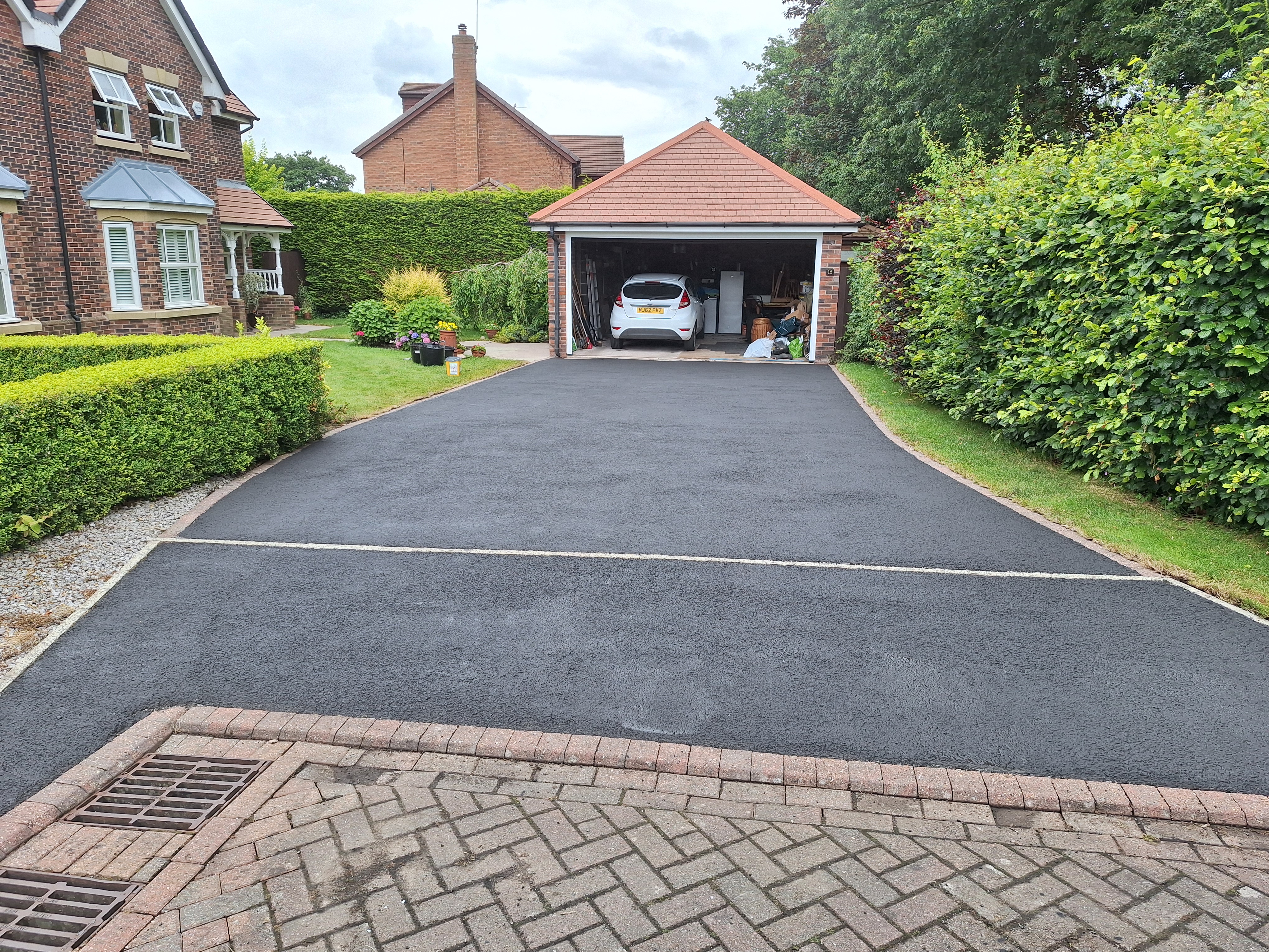 The same tarmac driveway after restoration, with a renewed dark finish.